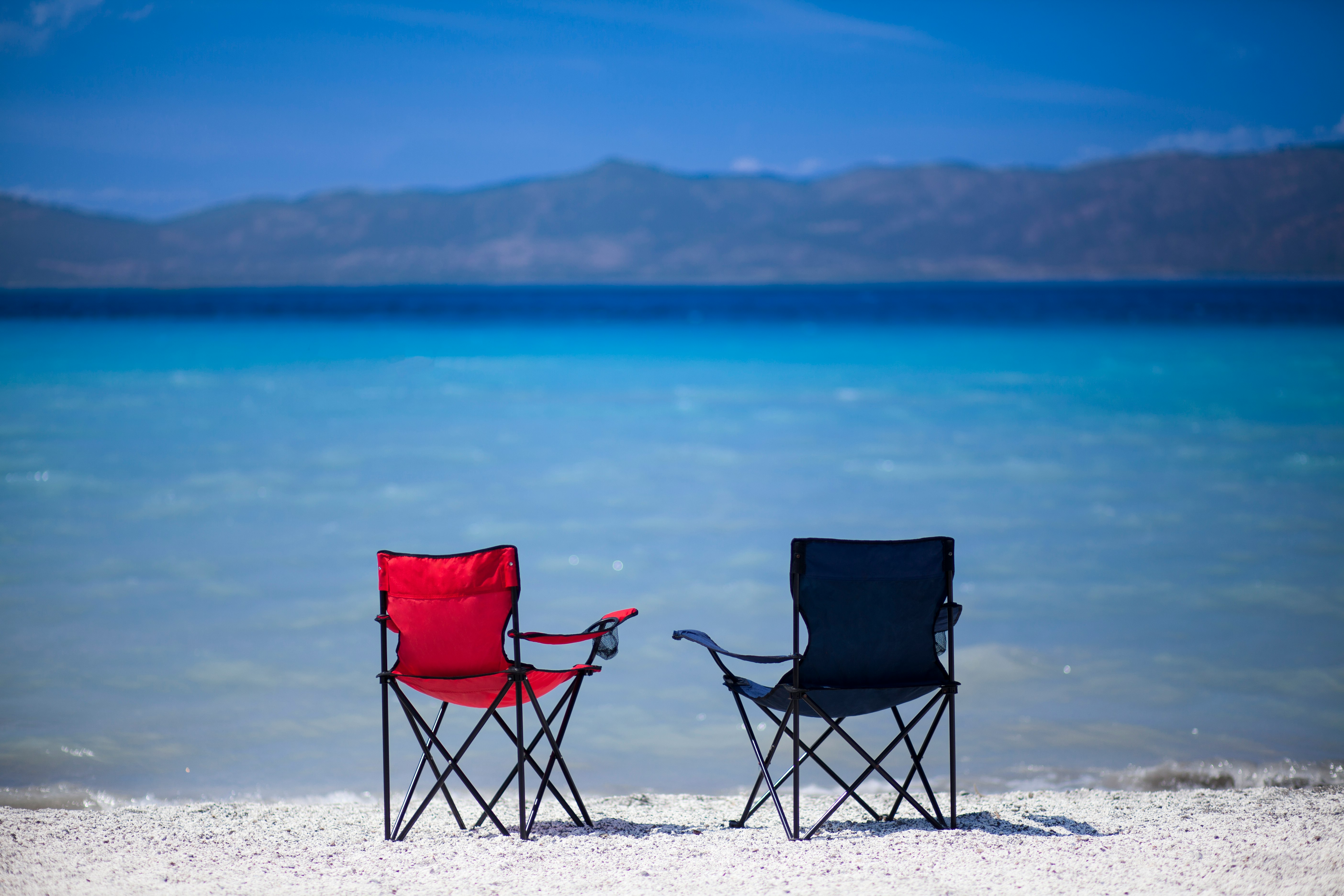 red and black folding chair on white sand during daytime